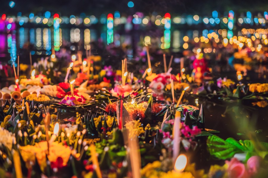 Candle-lit krathong floating on water during Loy Krathong