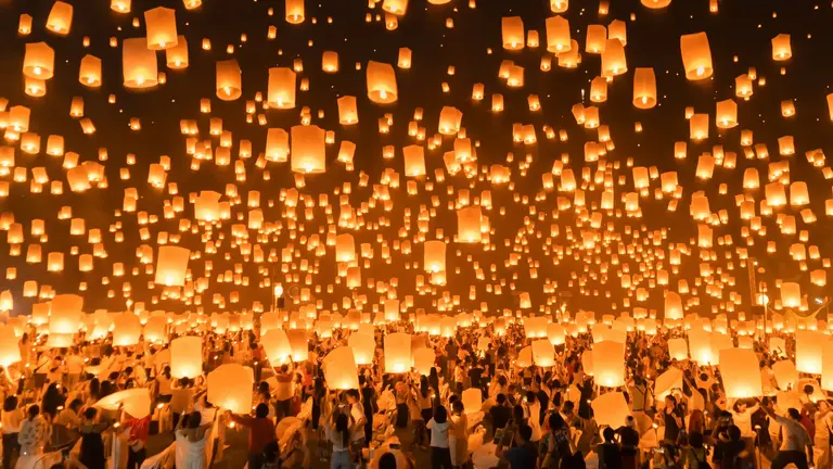 Sky lanterns rising into the night during Yi Peng